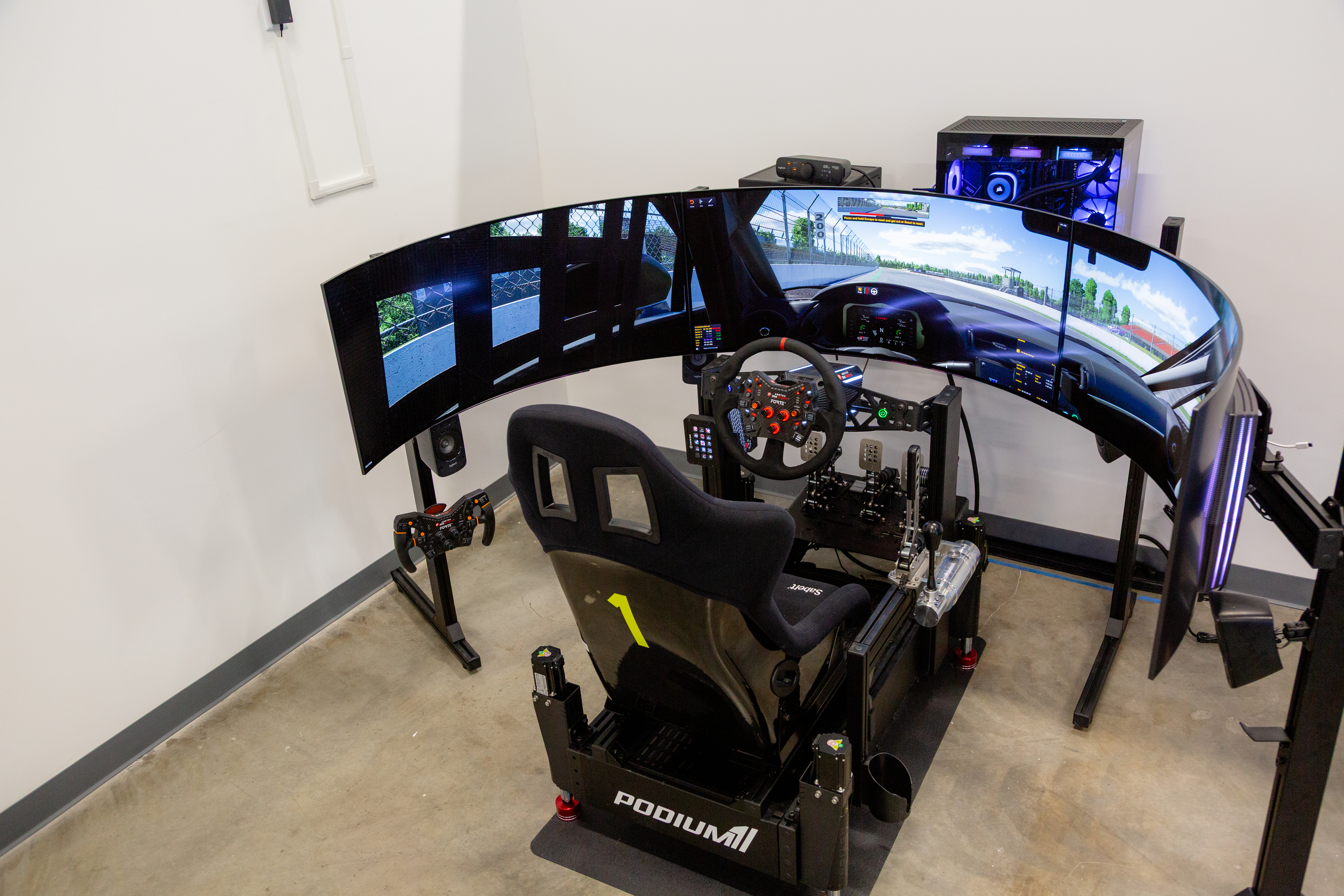 Elite cockpit — Sabelt seat, triple curved monitors, Asetek Invicta wheel, motion actuators